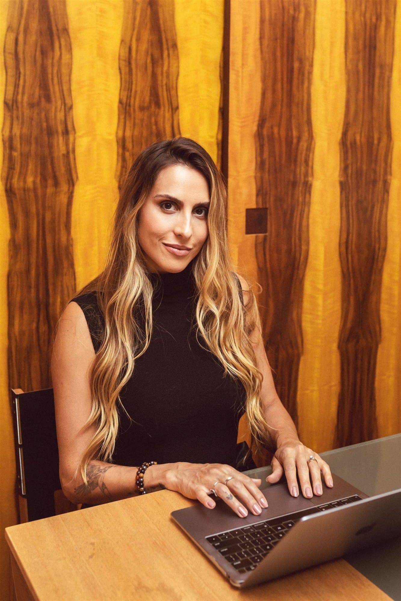 Xanda Fogaça sentada à mesa, digitando em um laptop